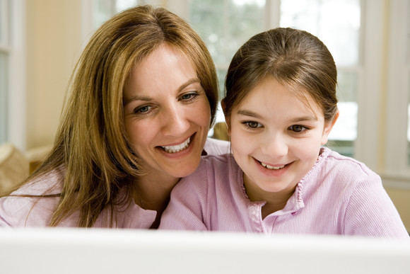 Mother and young daughter tooling at a computer screen together