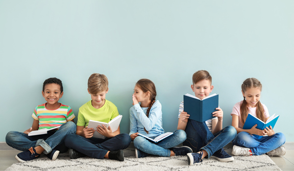 five children sit reading in front of a blue wall