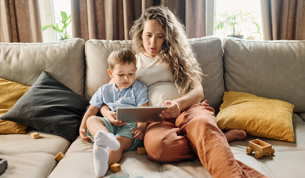 Young pregnant woman and little boy looking at a tablet computer.