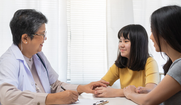 A female doctor holds her patient's hand for encouragement in clinical meeting.