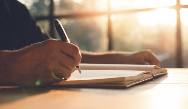 Person writing in a journal at a desk.