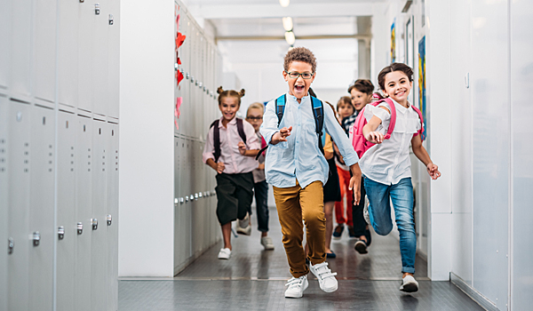 Happy school children running through a corridor.
