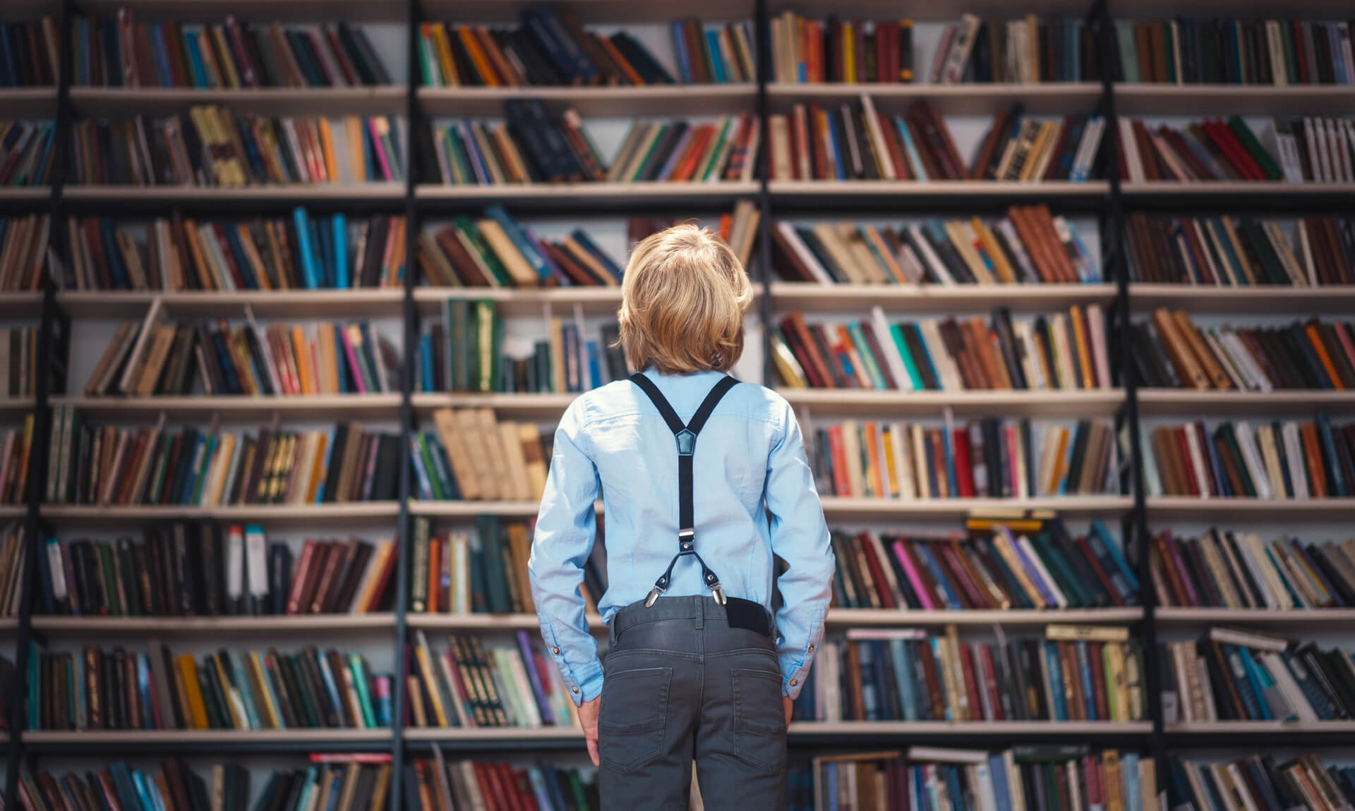 Boy looks at a wall of books.