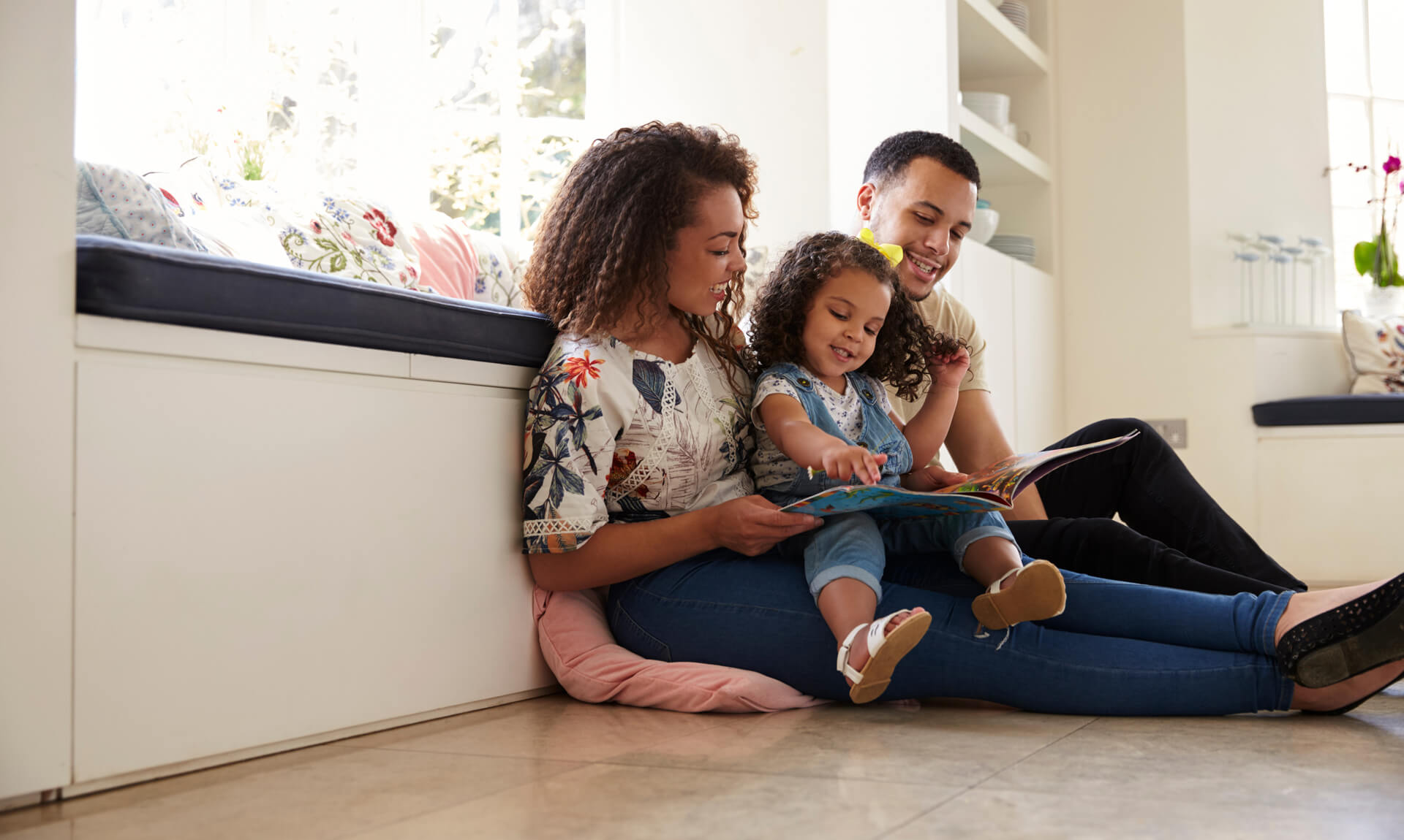 A Family Guide to Building Language Comprehension Through Reading Aloud Parents and their daughter sitting on the floor reading a book