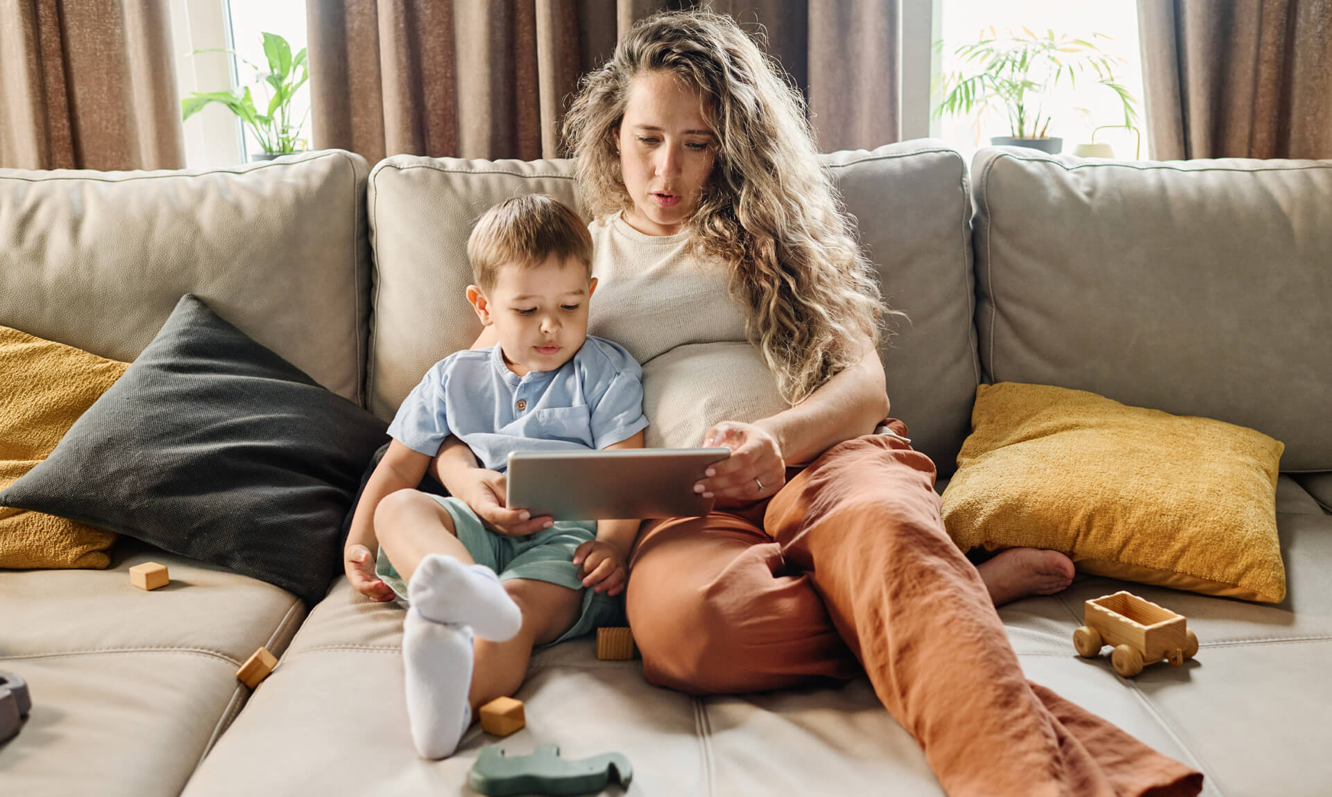 Young pregnant woman and little boy communicating in video chat while resting at home.