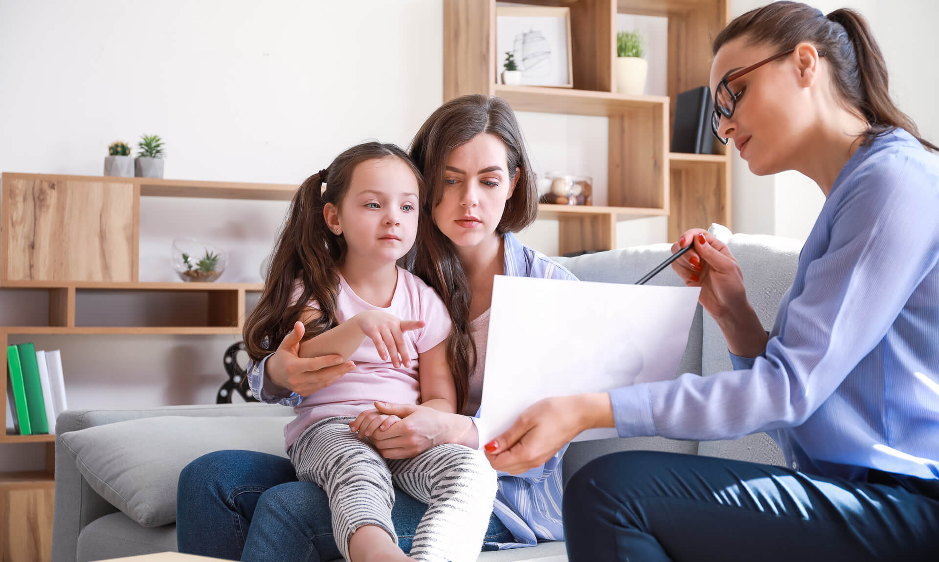 Female therapist working with mother and daughter in office.