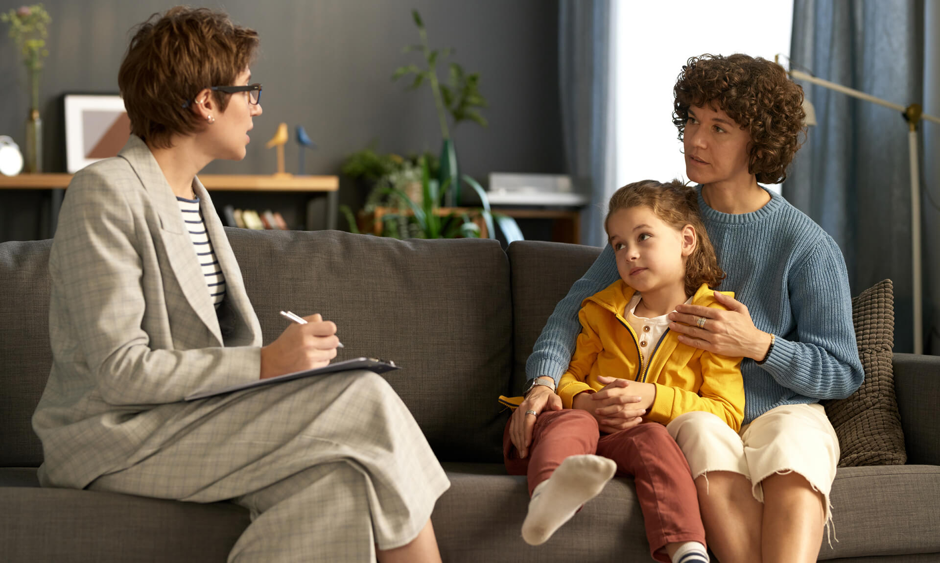 What to Expect in a Dyslexia Evaluation Therapist making notes while talking to a parent and child during a meeting.