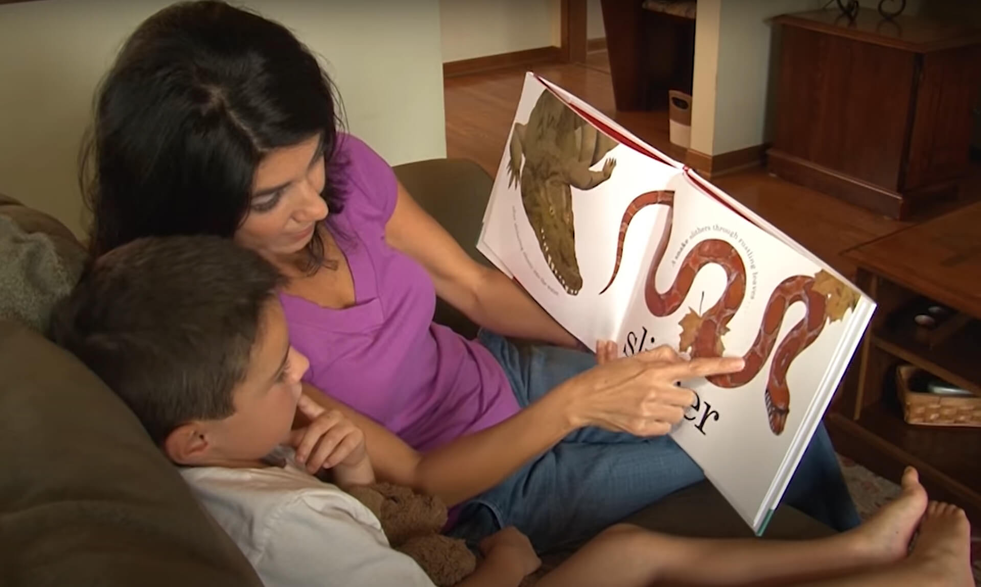 Phonemic Awareness Mom points out a detail in a book she is reading to her young son.