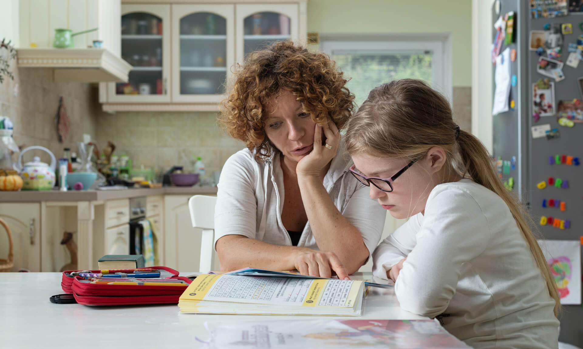Mother helping daughter with her homework at the table in the dinning room.