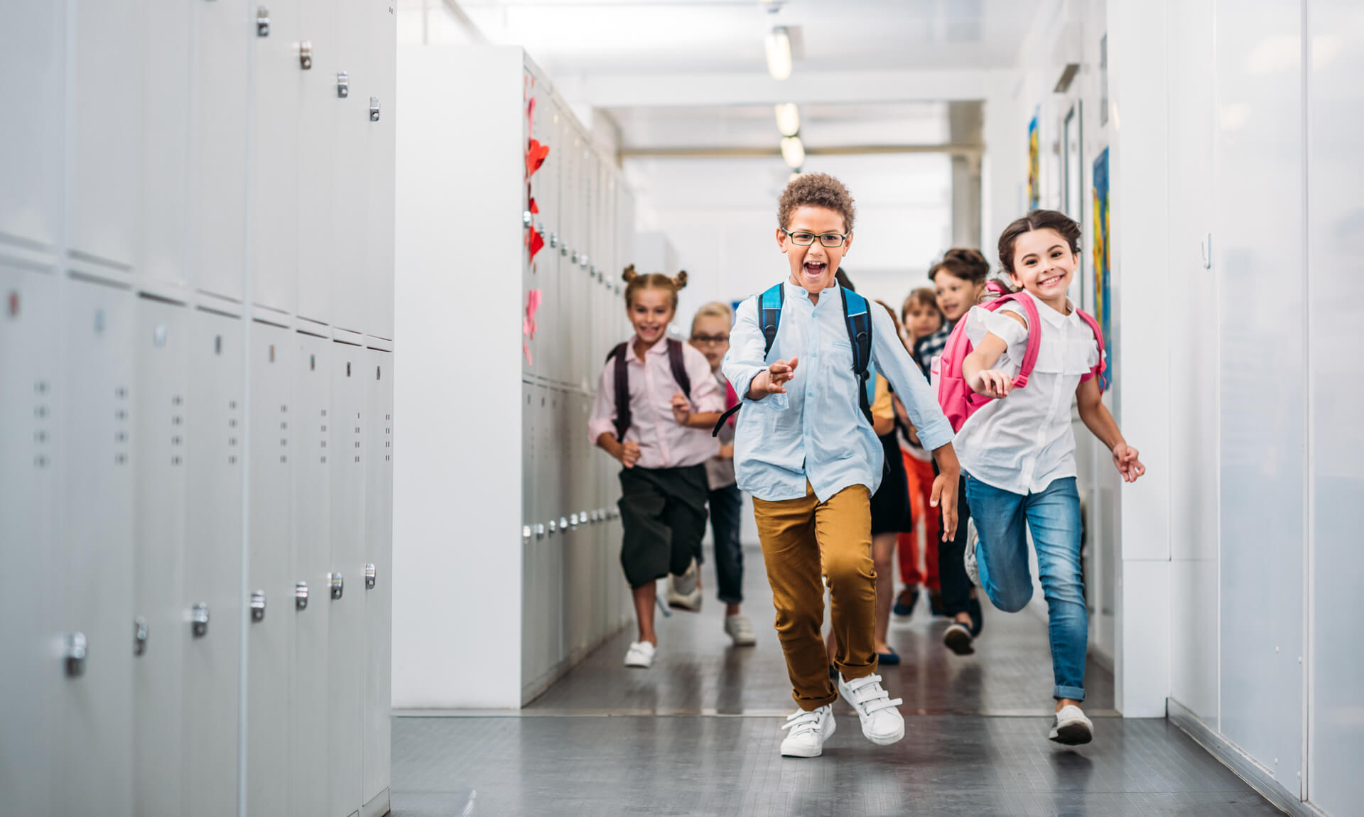 Young students running through school corridor.
