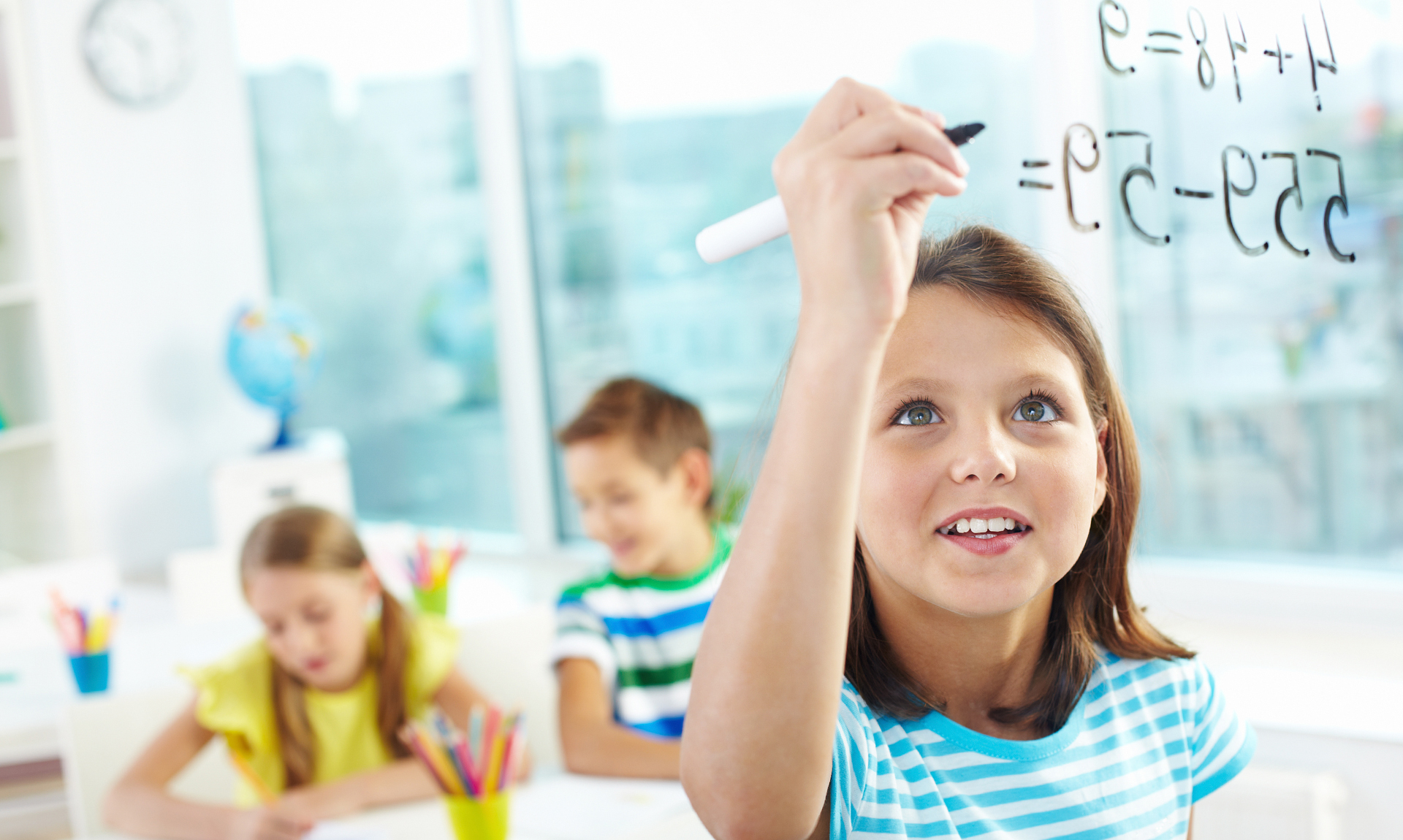 child writes equation while students study in background