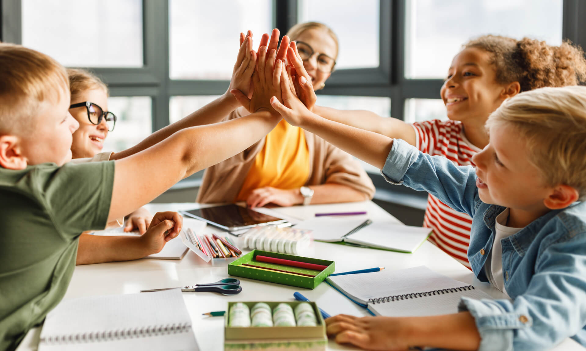 happy students celebrate success around table in classroom