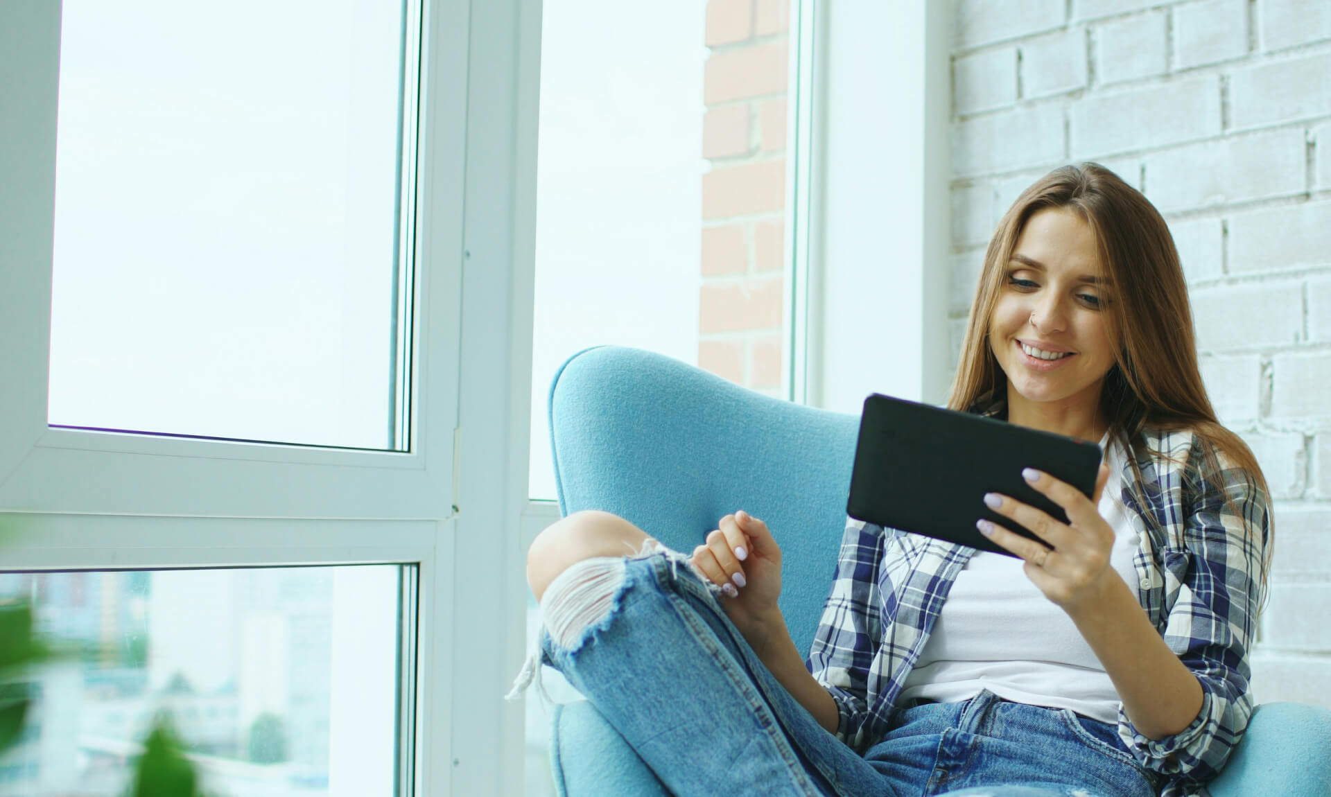 woman sits in chair reading from a tablet