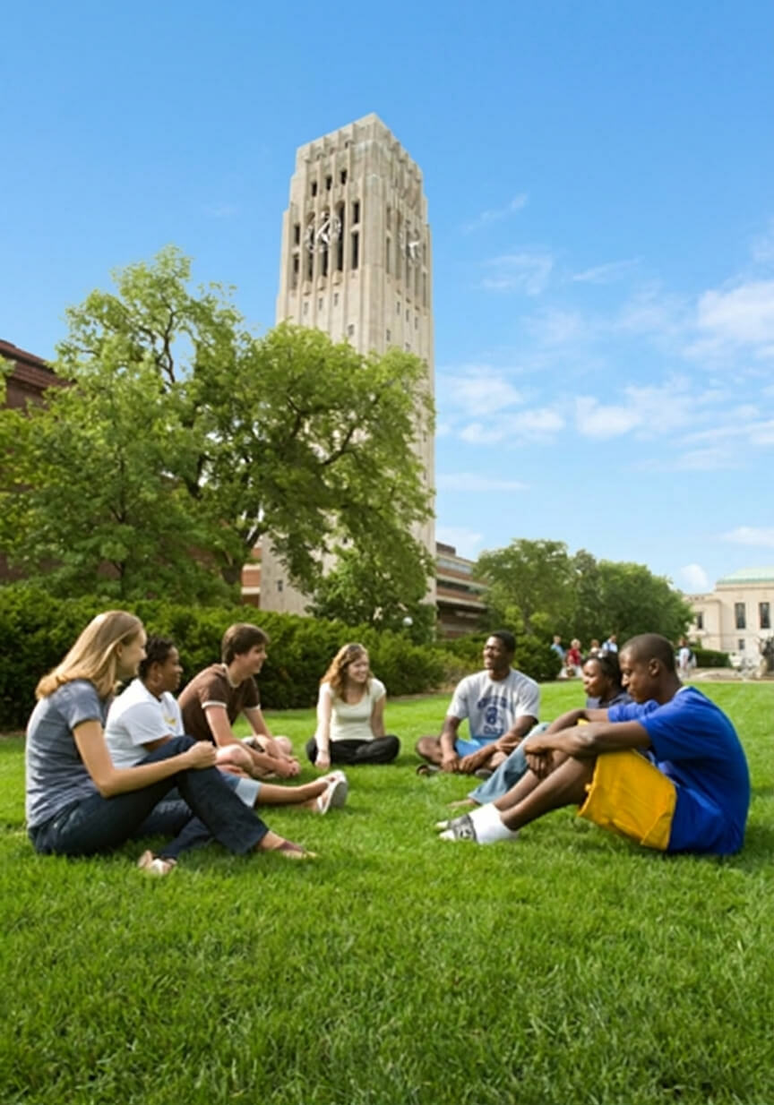 A group of students relax on the lawn in front of Burton Tower on the University of Michigan campus.