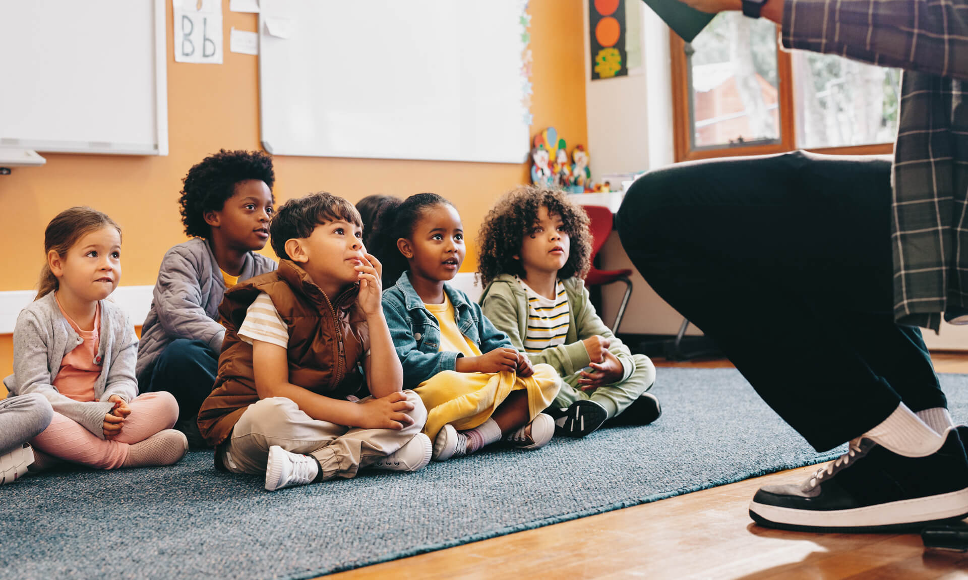 Elementary school students sit and listen to a story from their teacher